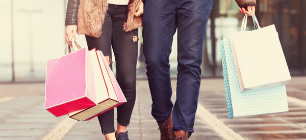 a couple holding hands and walking down the street with numerous shopping bags