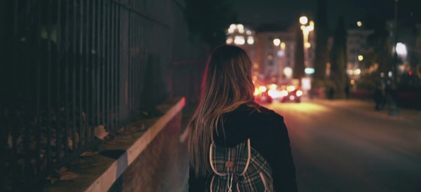 a girl walking down a dark city road by herself
