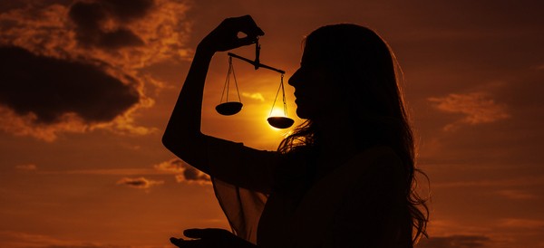 a woman holding the scales of justice against a setting sun