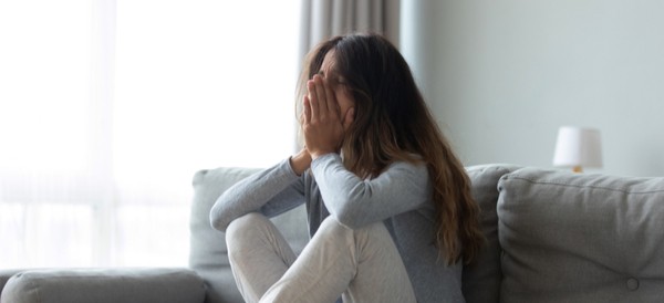 a woman looking upset sitting on a couch by herself