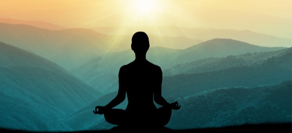 a woman sitting on a mountain meditating