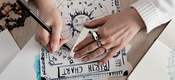 a woman working on her zodiac birth chart in watercolor and pen