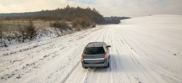 an suv driving along a snow covered dirt road in the winter