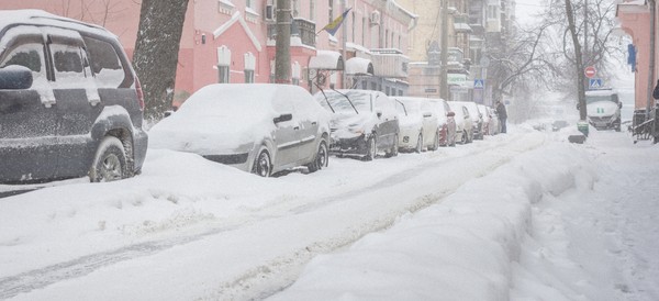 cars on a street in a city covered in snow