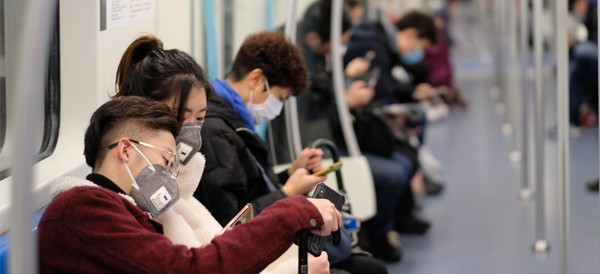 people sitting on a train wearing face masks spreading the coronavirus