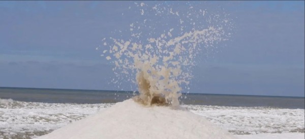 an ice volcano on the coast of Lake Michigan erupting with slushy snow