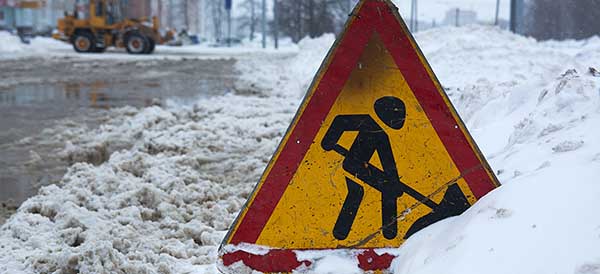 a road sign signaling work standing in the snow